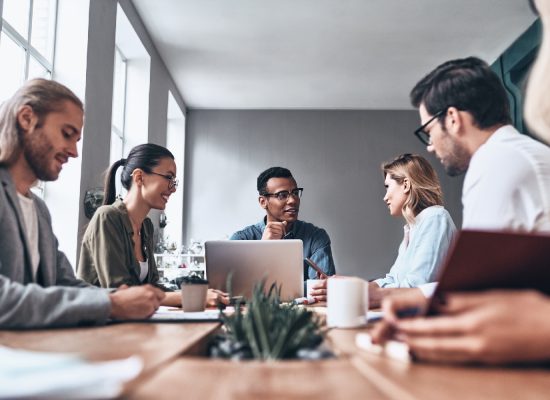 Group of young modern people in smart casual wear discussing business while working in the creative office